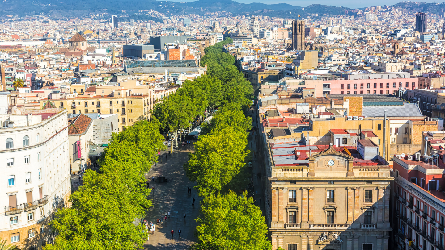 Die belebte Flaniermeile La Rambla in Barcelona mit ihren Bäumen, Straßenkünstlern und historischen Gebäuden